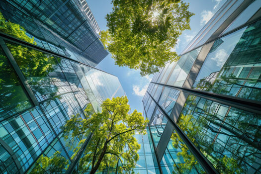Low angle shot of modern glass building and green trees against